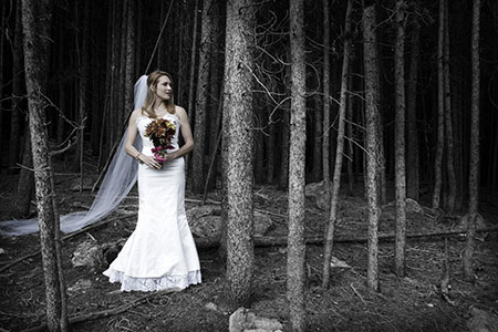 Bride in gown and bouquet standing in woods Bride in gown and bouquet standing in woods