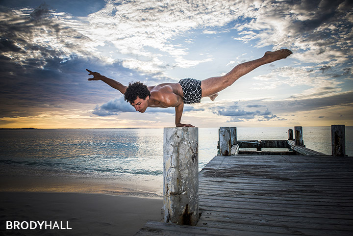 Male acrobat performing on a pier at Club med in the Turks & Caicos islands Male acrobat balancing on one hand on a pier at Club med in the Turks & Caicos islands