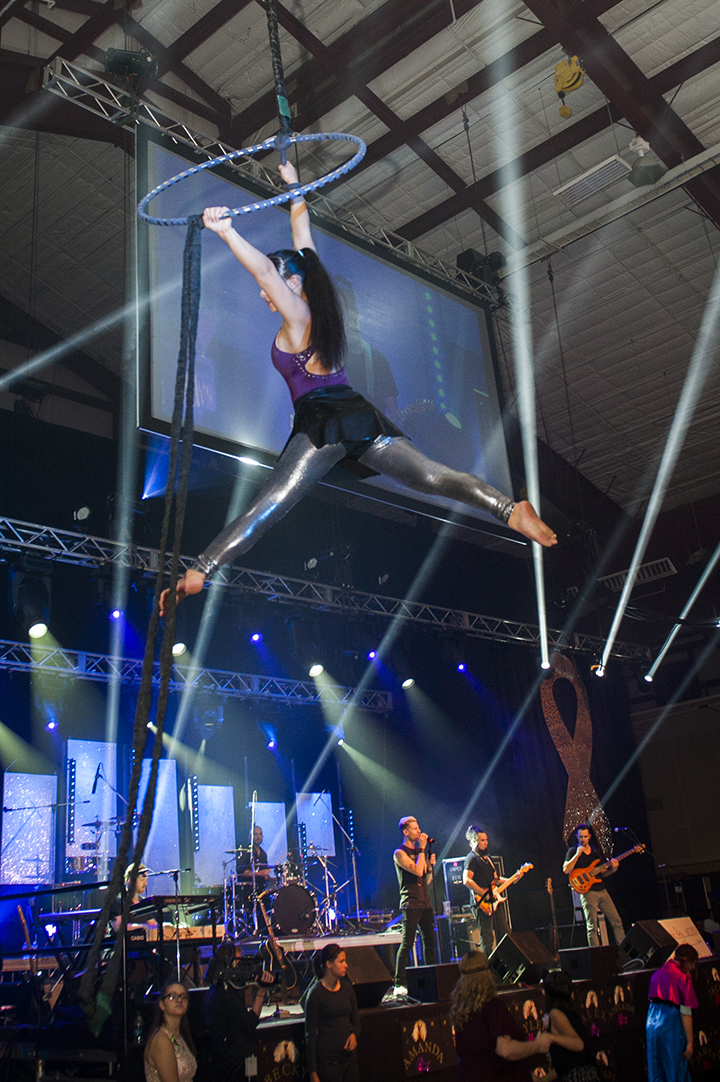 Female aerial performer hanging above a band at a concert In Castle Rock, CO.